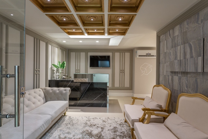 Sala de espera com poltronas douradas e parede de mármore